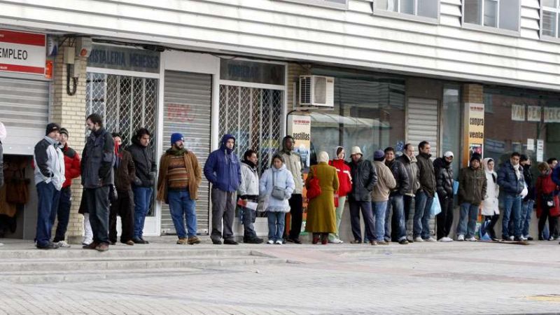 Varias personas forman una larga cola ante una oficina del antiguo INEM.