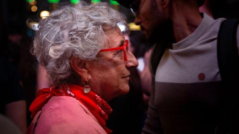 Una mujer observa a las personas que se manifiestan por el derecho a la vivienda en la Puerta del Sol. Tamara Rozas