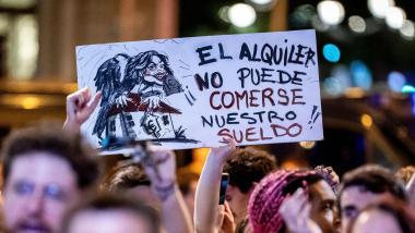 Una persona muestra una pancarta durante una cacerolada por la vivienda. EP.