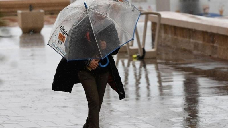 Una mujer se resguarda de la lluvia bajo un paraguas. EP.