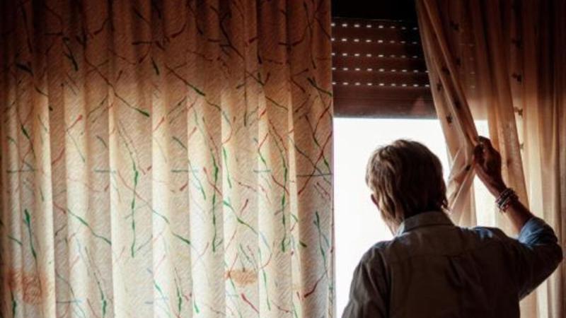 Un hombre mayor observa la calle desde su ventana. © Fundación ”la Caixa”