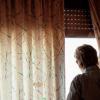 Un hombre mayor observa la calle desde su ventana. © Fundación ”la Caixa”