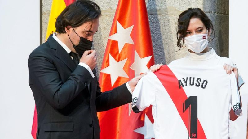 La presidenta de la Comunidad de Madrid, Isabel Díaz Ayuso, posa con una camiseta de fútbol con su nombre y con el presidente del Rayo Vallecano, Raúl Martín Presa (i), tras su ascenso a Primera División. EP/Archivo.