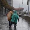 Vecinos de Barcelona pasean bajo la lluvia en la playa de la Barceloneta durante el temporal. EP.