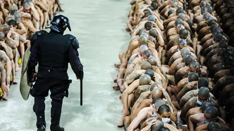Una fotografía proporcionada por la Presidencia de El Salvador muestra a un agente de policía vigilando a reclusos con mascarillas durante un operativo policial en el Centro Penal Izalco. EP.
