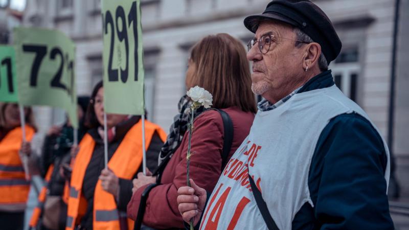 Una personas sostiene una flor durante una concentración de asociaciones y sindicatos en recuerdo a las 7.291 víctimas en las residencias de mayores en la Comunidad de Madrid durante la pandemia. EP