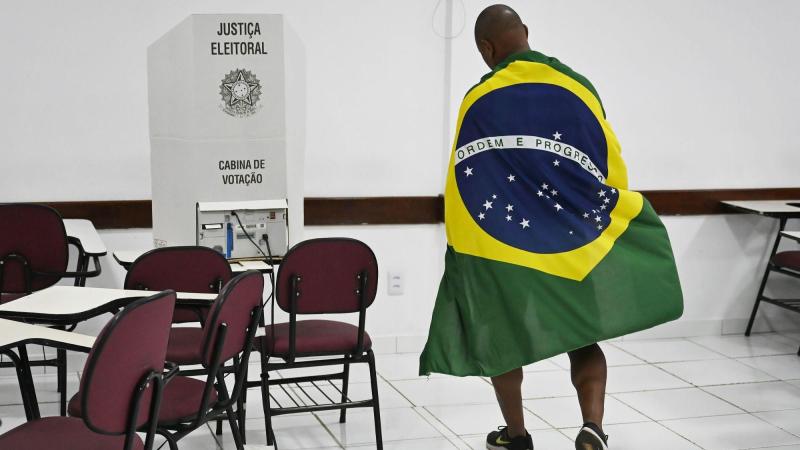 Un votante envuelto en la bandera nacional aparece en un centro de votación en Brasilia, Brasil. EP.
