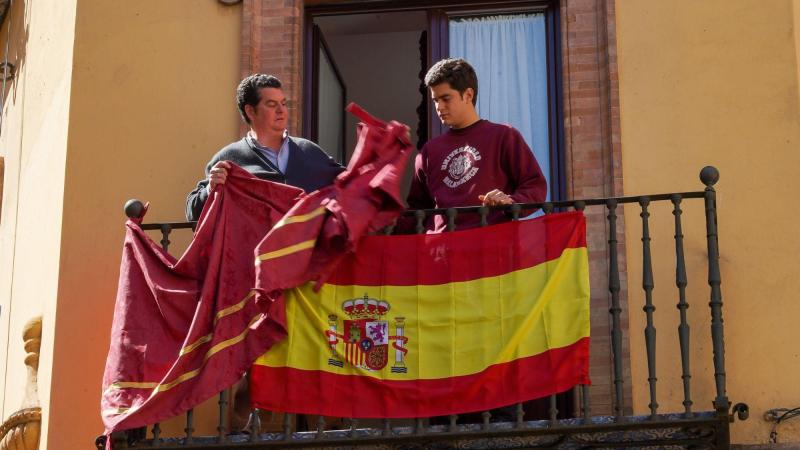 Vecinos de el centro de Sevilla adorna su balcón con colgaduras debajo de la bandera de España en vísperas de Semana Santa en 2020. Europa Press Archivo.
