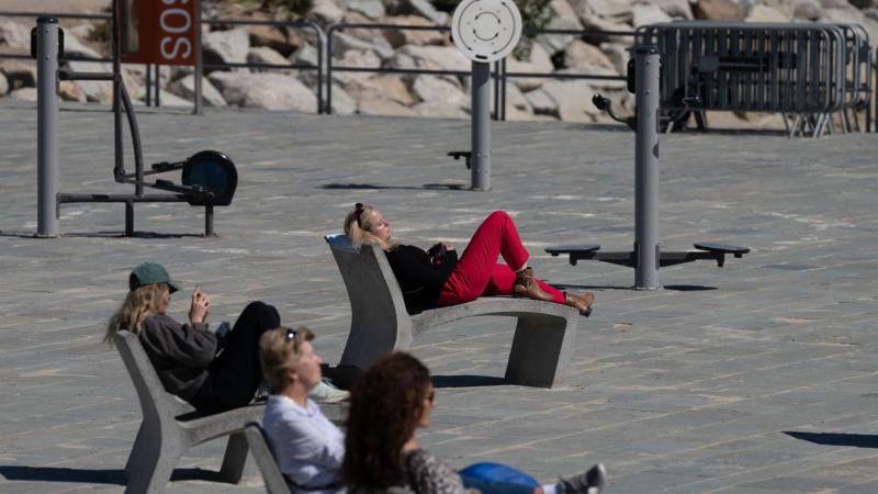 Varias personas toman el sol en el paseo marítimo de la playa del Bogatell. Europa Press   Archivo.