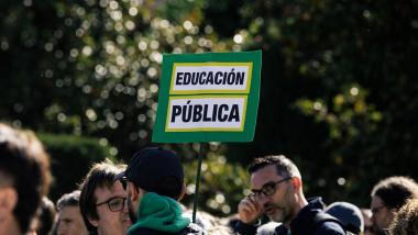 Una persona con una pancarta con lema 'Educación pública'. EP.