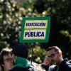 Una persona con una pancarta con lema 'Educación pública'. EP.
