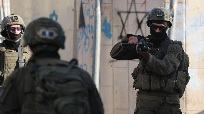 Soldados israelís retienen y apuntan a una familia palestina durante una incursión de colonos en la Ciudad Vieja de Hebrón. EP/Mosab Shawer.