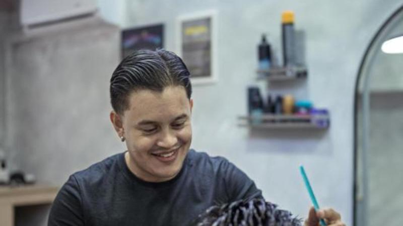 Juan interactuando con uno de sus clientes mientras le hace un corte de pelo. © Fundación ”la Caixa”