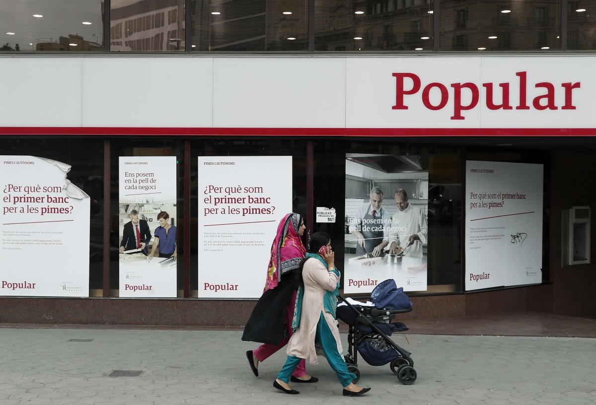 Unas mujeres pasan ante una oficina del Banco Popular en el Paseo de Gracia esquina con la calle Aragón de Barcelona