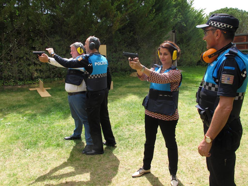 Un policía municipal observa a la alcaldesa de Teruel, Emma Buj (PP), disparar un arma en unas prácticas de tiro.