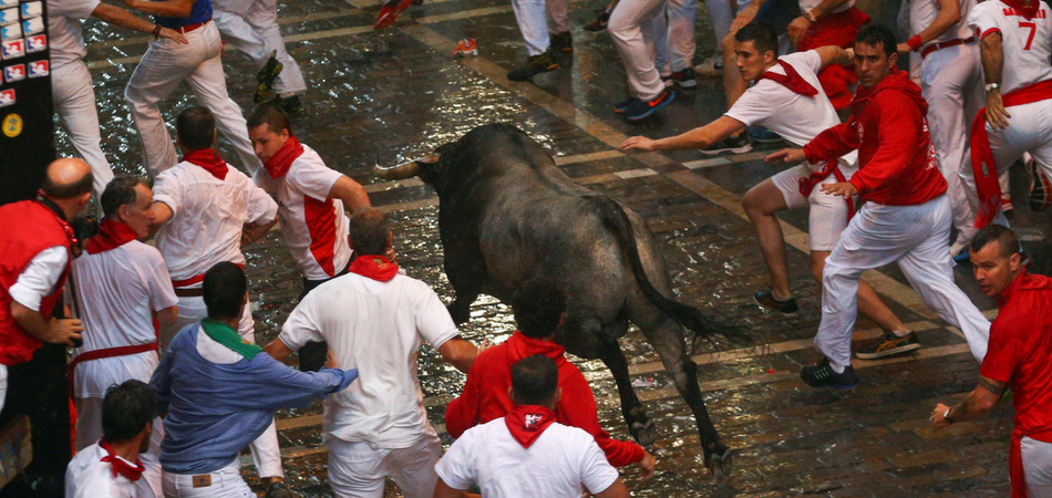 Corredores y toros a su paso por la plaza del Ayuntamiento, con toros de la ganadería de José Escolar, durante el segundo encierro de San Fermín en Pamplona