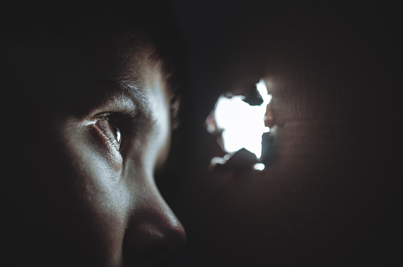 Una joven mira a través de un agujero. Foto: Dmitry Ratushny en Unsplash