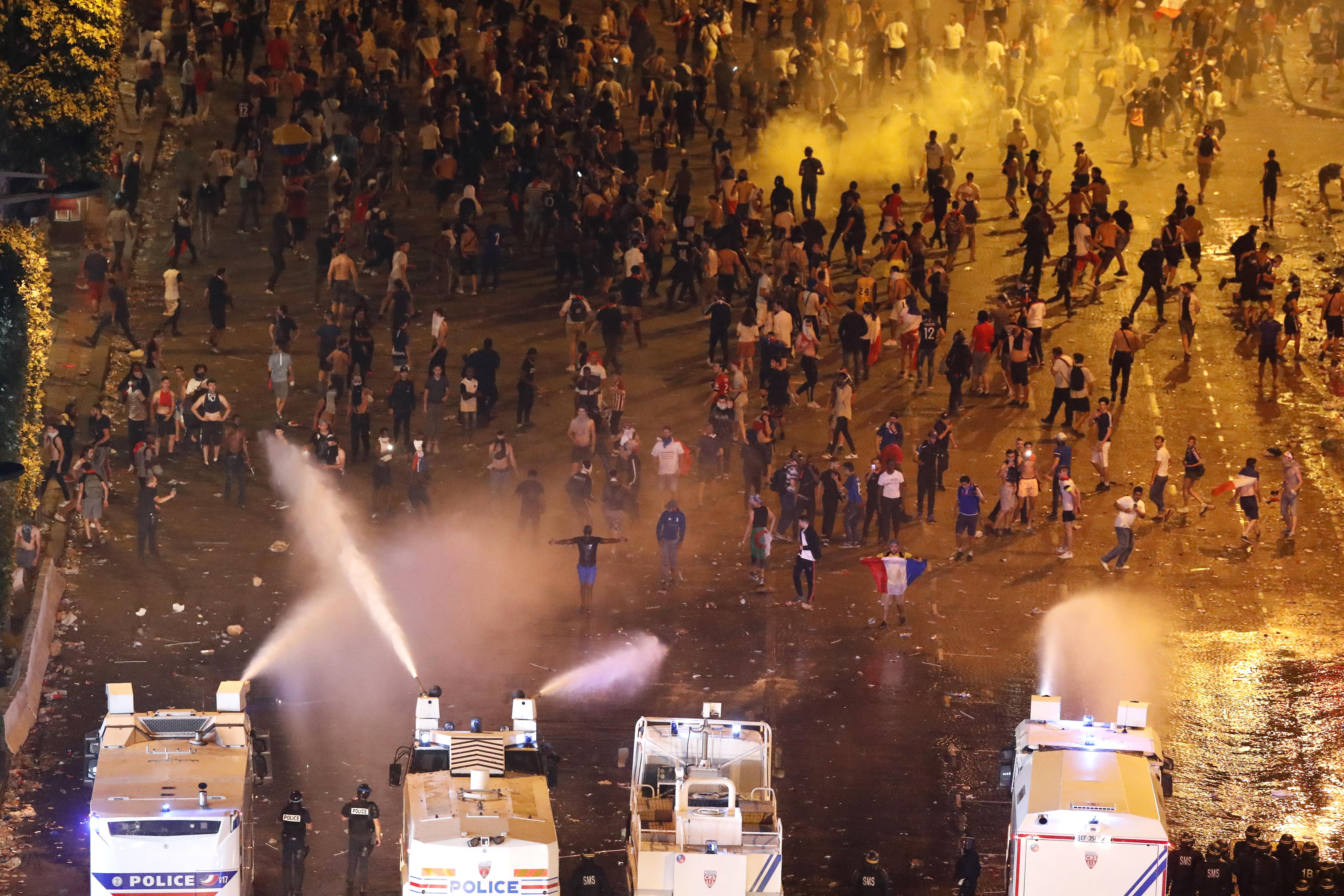 La policía antidisturbios francesa utiliza camiones de agua para dispersar a la gente en la avenida de los Campos Elíseos durante la celebración