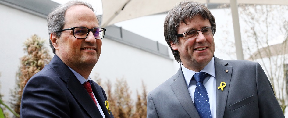 El presidente de la Generalitat de Cataluña, Quim Torra (izq), estrecha la mano a su predecesor, el expresidente regional catalán Carles Puigdemont. EFE/Archivo