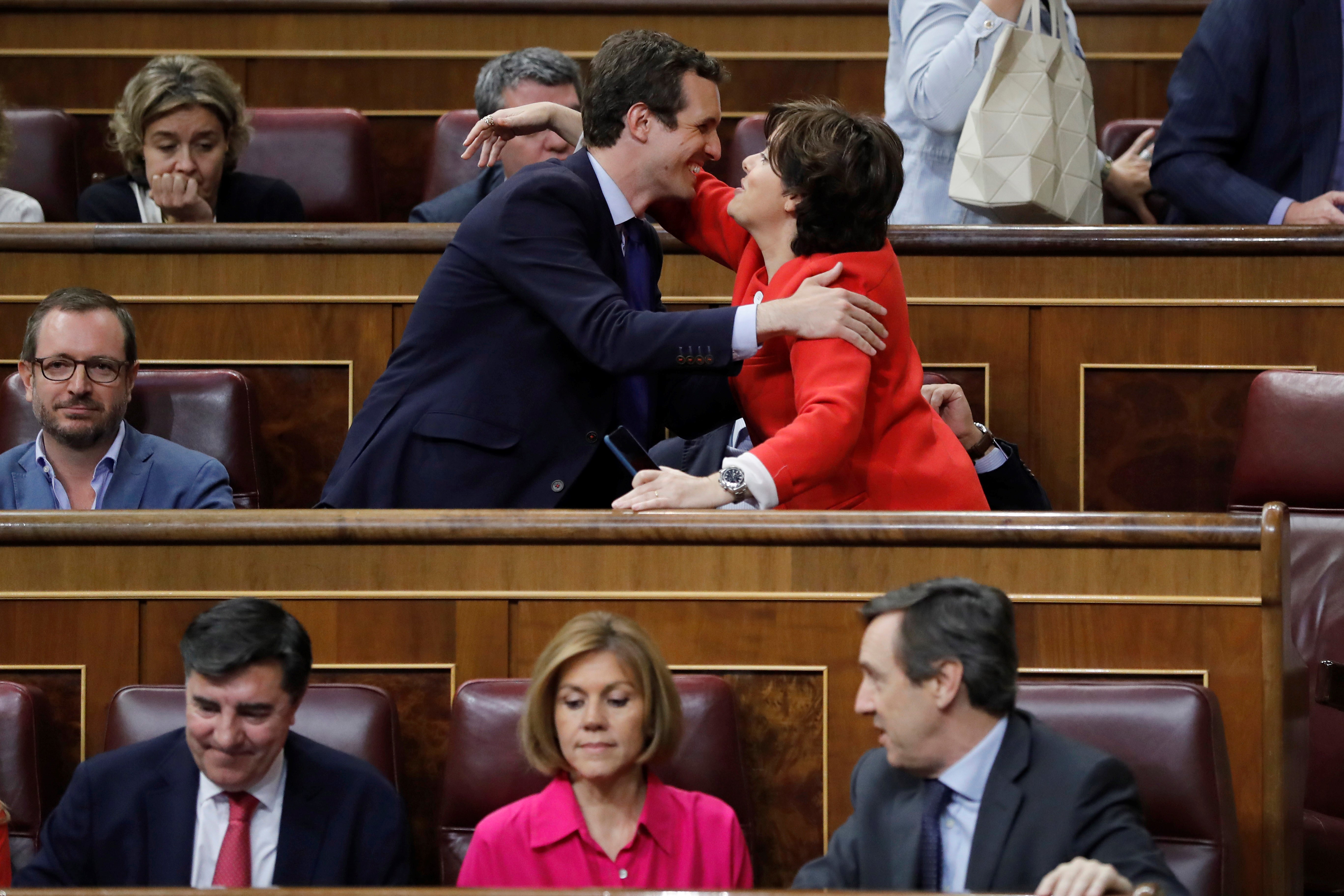 La candidata a liderar al PP, Soraya Sáenz de Santamaría (d), saluda al también candidato, Pablo Casado (i), durante un pleno, debajo María Dolores de Cospedal. EFE/Archivo