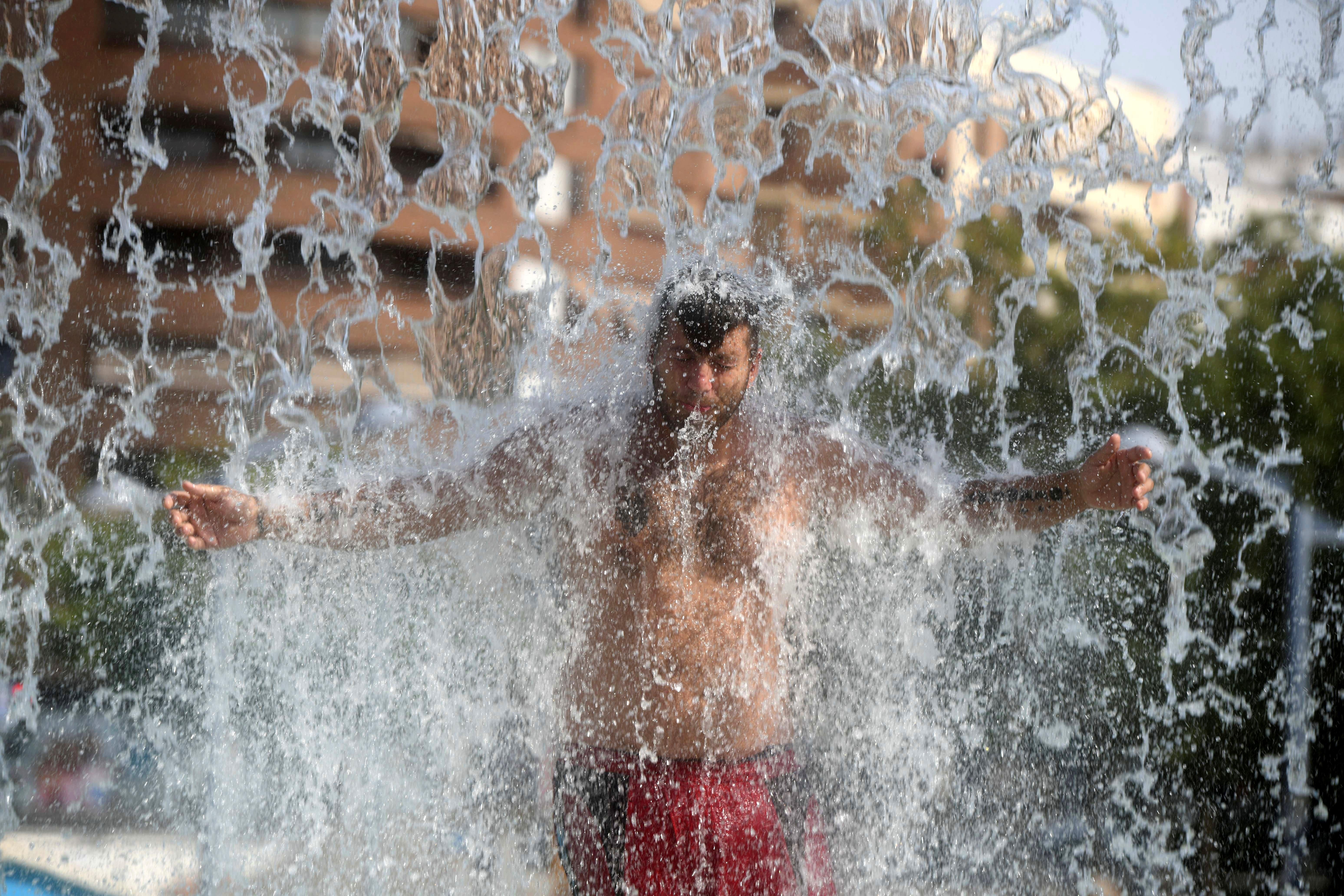 Un hombre se refresca en una fuente pública de Córdoba