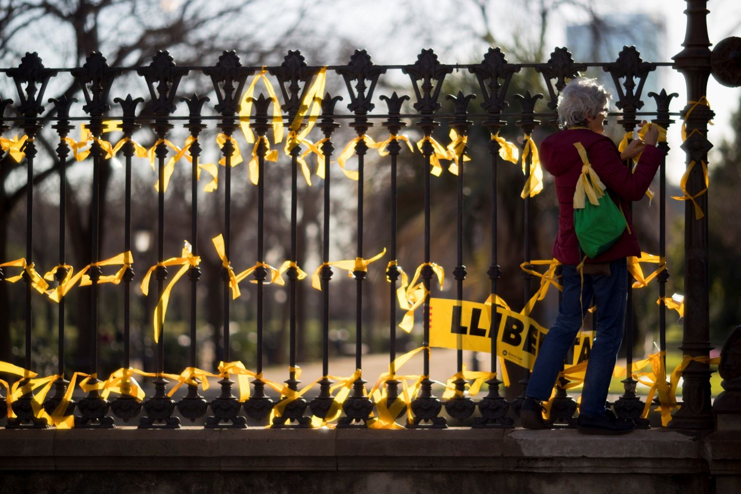 Una mujer coloca lazos amarillos en la verja del Pac de la Ciutadella, en el Paseo de Lluís Companys, en Barcelona. EFE/Archivo