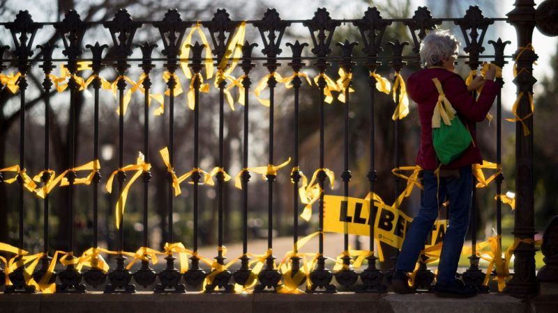 Una mujer coloca lazos amarillos en la verja del Pac de la Ciutadella, en el Paseo de Lluís Companys, en Barcelona. EFE/Archivo