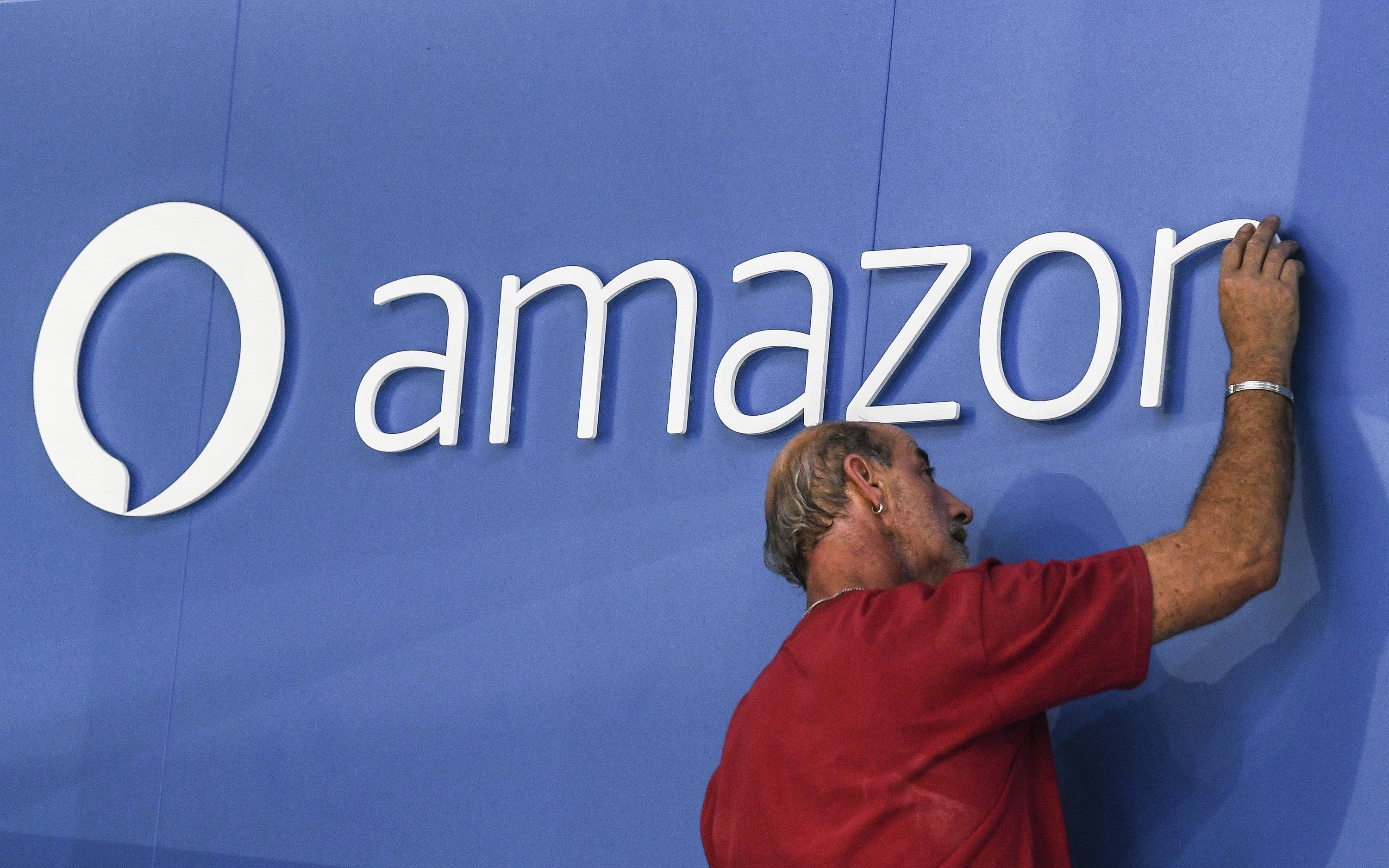 Un empleado retoca un cartel de Amazon. EFE