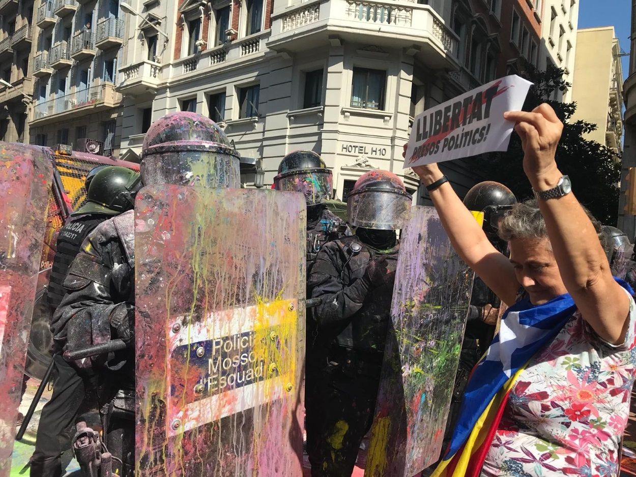 Una manifestante enarbola un cartel con la inscripción Llibertat presos polítics frente a un Mosso d Esquadra en el marco de la manifestación soberanista y la convocada por el sindicato policial Jusapol. EP