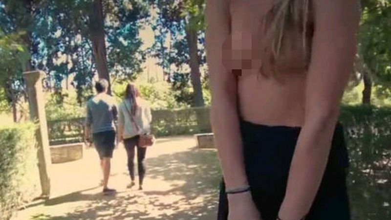Fotograma de la película porno junto a un par de turistas de fondo Fotograma de la película porno junto a un par de turistas de fondo