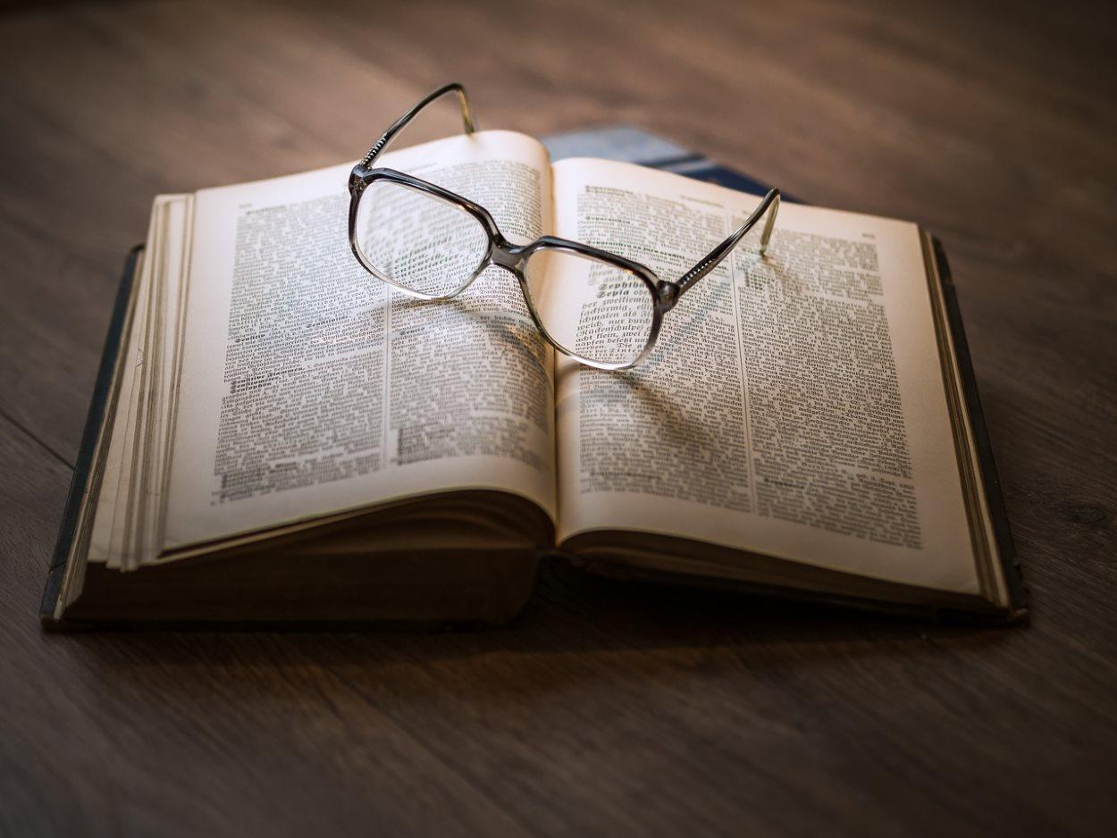Un libro abierto y, sobre él, unas gafas. Pixabay
