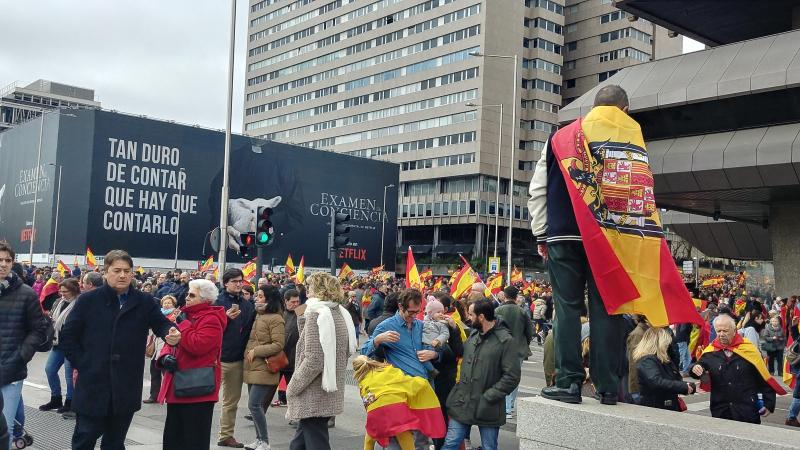 Un hombre ataviado con una bandera franquista en la manifestación de Colón.