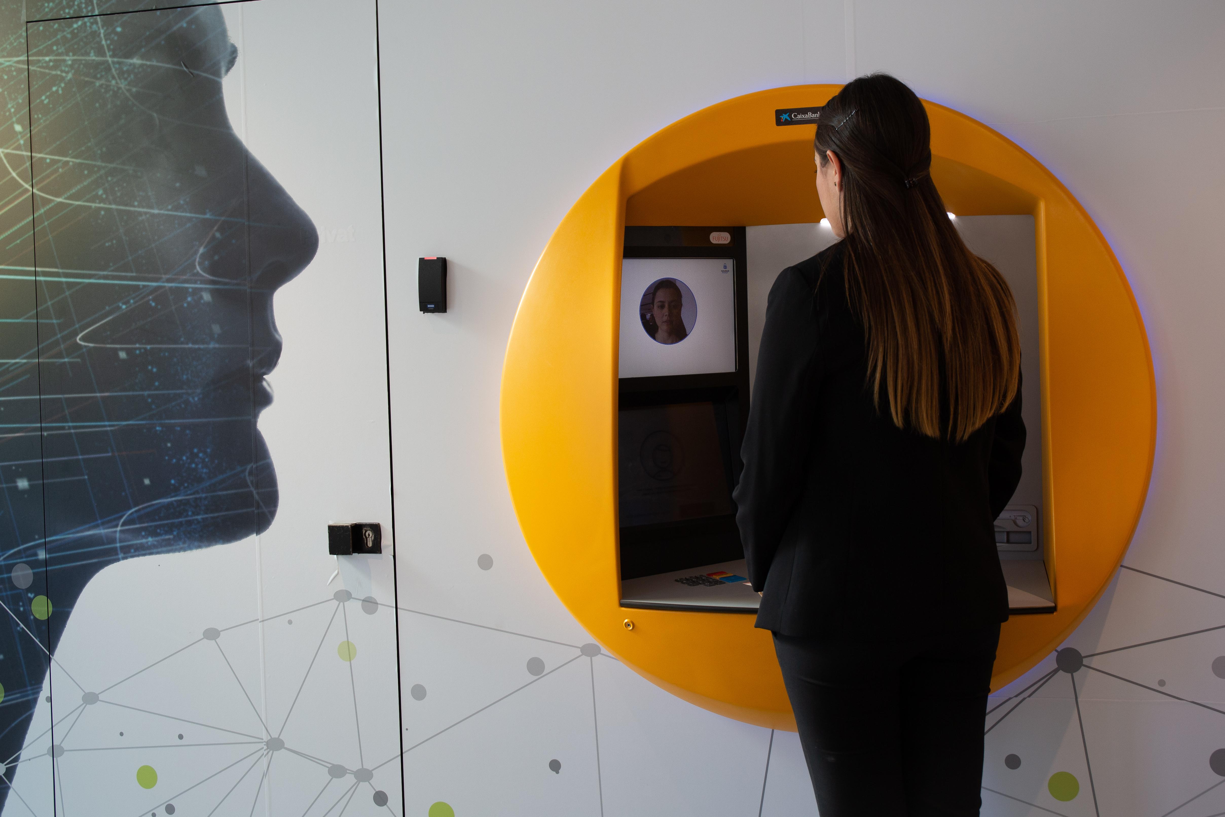 Una mujer utiliza en un cajero de CaixaBank el nuevo servicio de la compañía basado en reconocimiento facial 