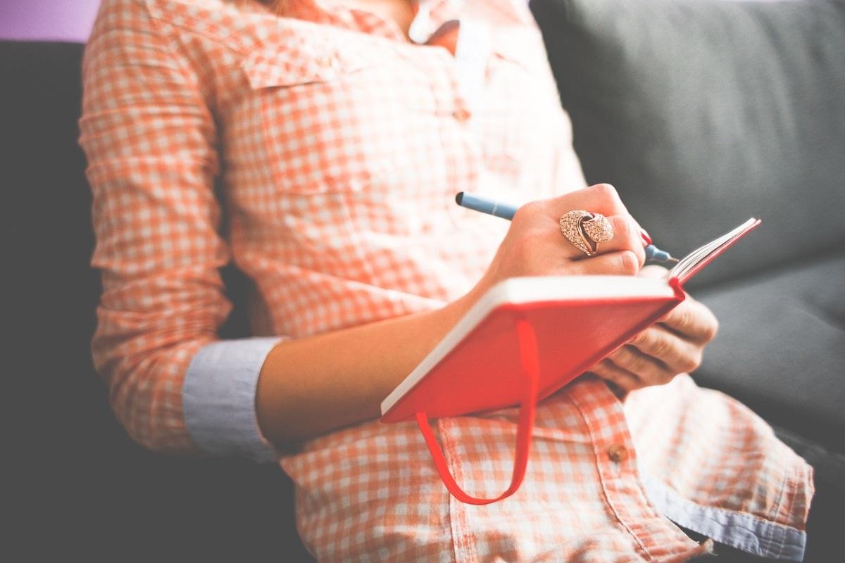 Una mujer escribe en un cuaderno. 