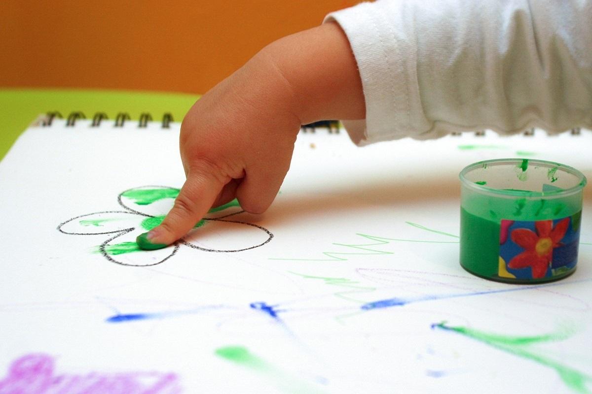 Un bebé pinta con los dedos en una escuela de educación infantil - EP
