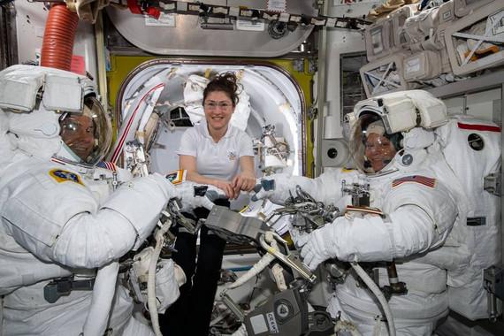 La astronauta de la NASA Christina Koch (centro) asiste a sus compañeros astronautas Nick Hague (izquierda) y Anne McClain (derecha) para ajustar los trajes espaciales poco antes de comenzar su primer paseo espacial el pasado 22 de marzo. / NASA