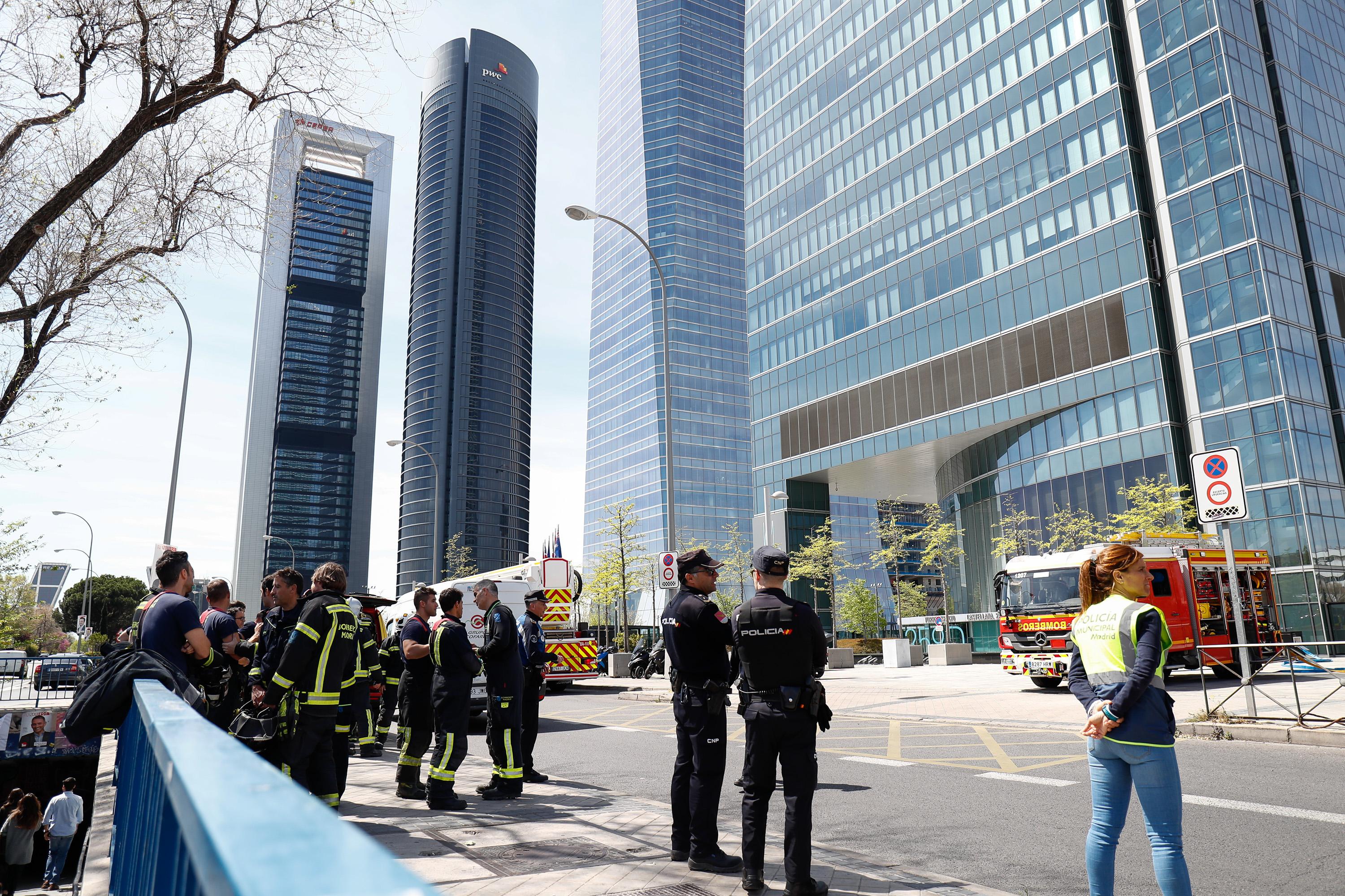 Bomberos del Ayuntamiento de Madrid y agentes de la Policía Nacional en las inmediaciones de la Torre Espacio (la cuarta de las torres del Paseo de la Castellana de Madrid) desalojada por una 