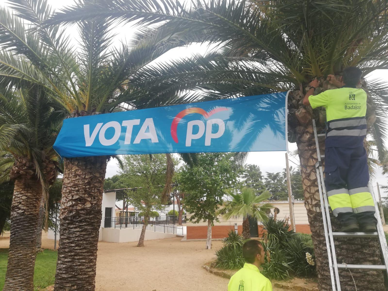 Trabajadores municipales colgando pancartas electorales del PP