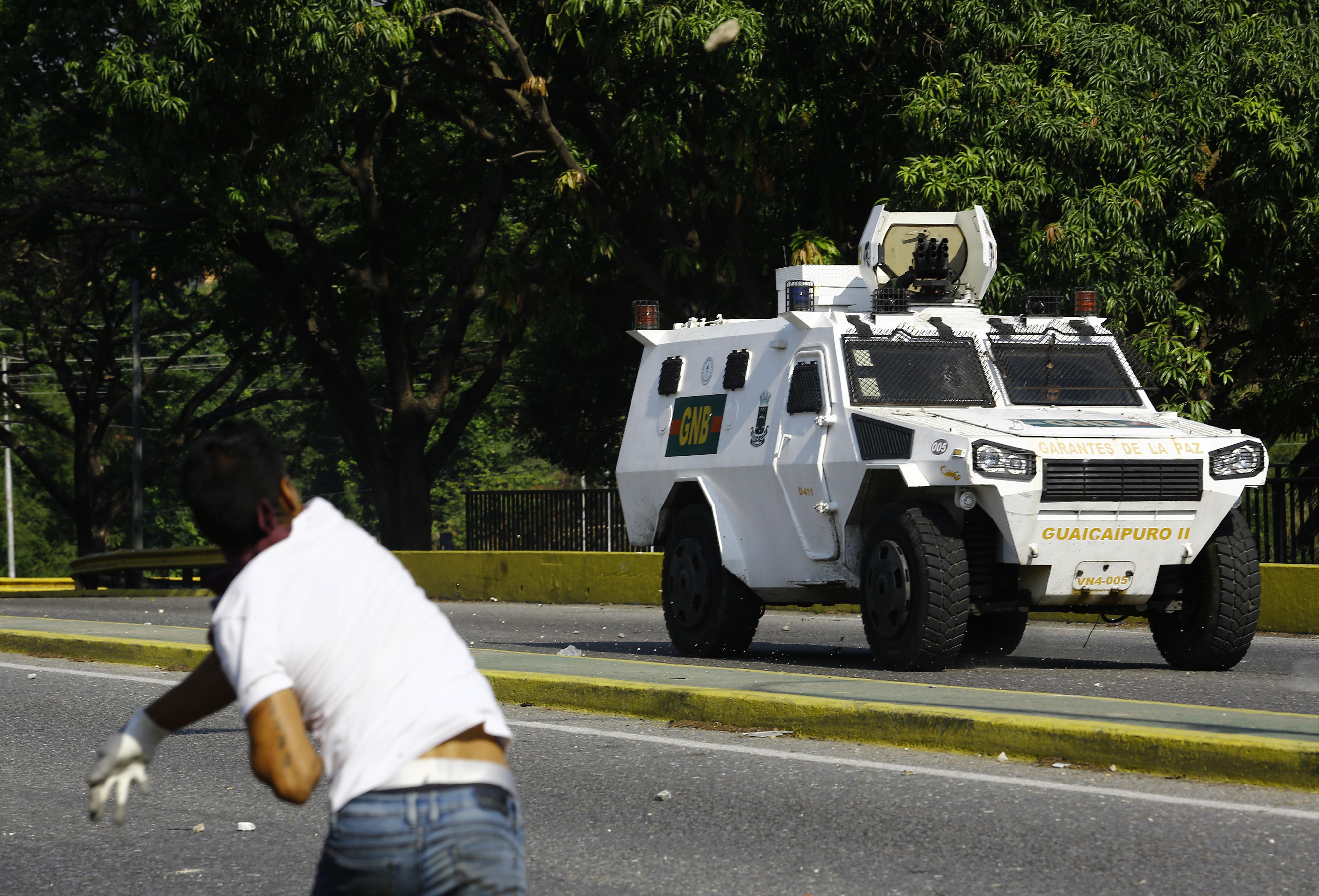 Un opositor lanza un proyectil a un coche del ejército venezolano