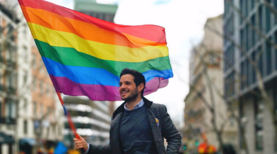 Pablo Sarrión López con una bandera LGTBi en la calle Génova. Twitter