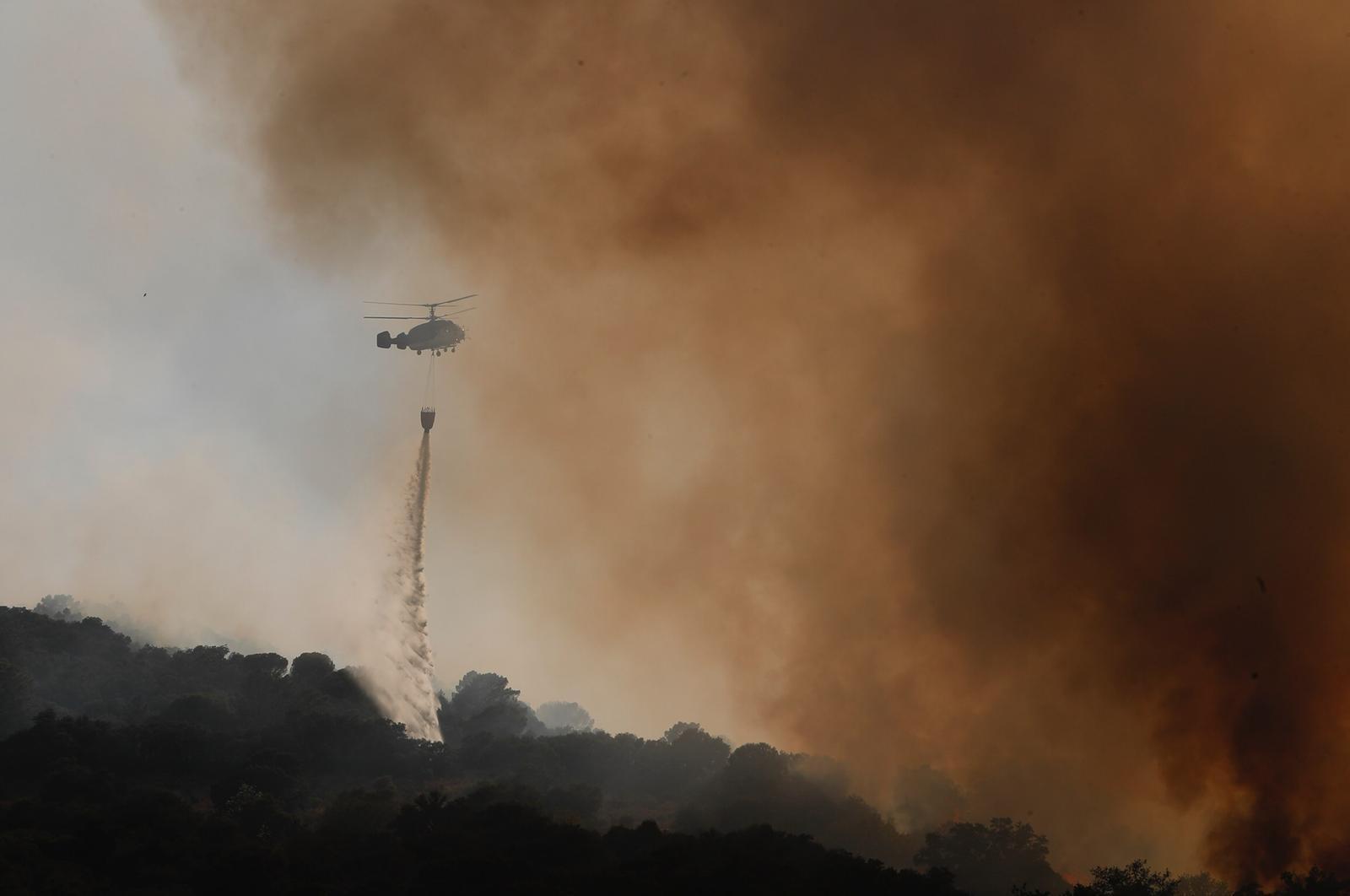 Un helicóptero vierte agua entre las llamas, que han quemado ya 2.500 hectáreas en la Comunidad de Madrid.