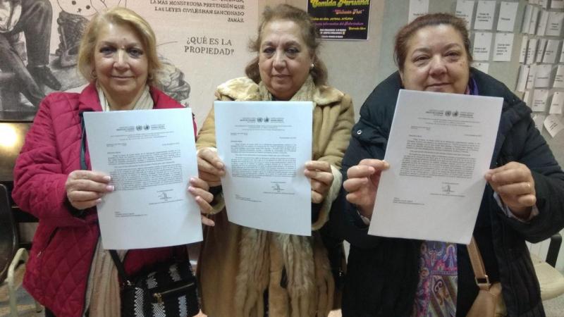 Pepi Santiago, a la izquierda, junto a su cuñada Juana y su hermana Rosi, mostrando los documentos de la ONU que ilegalizan sus desahucios.
