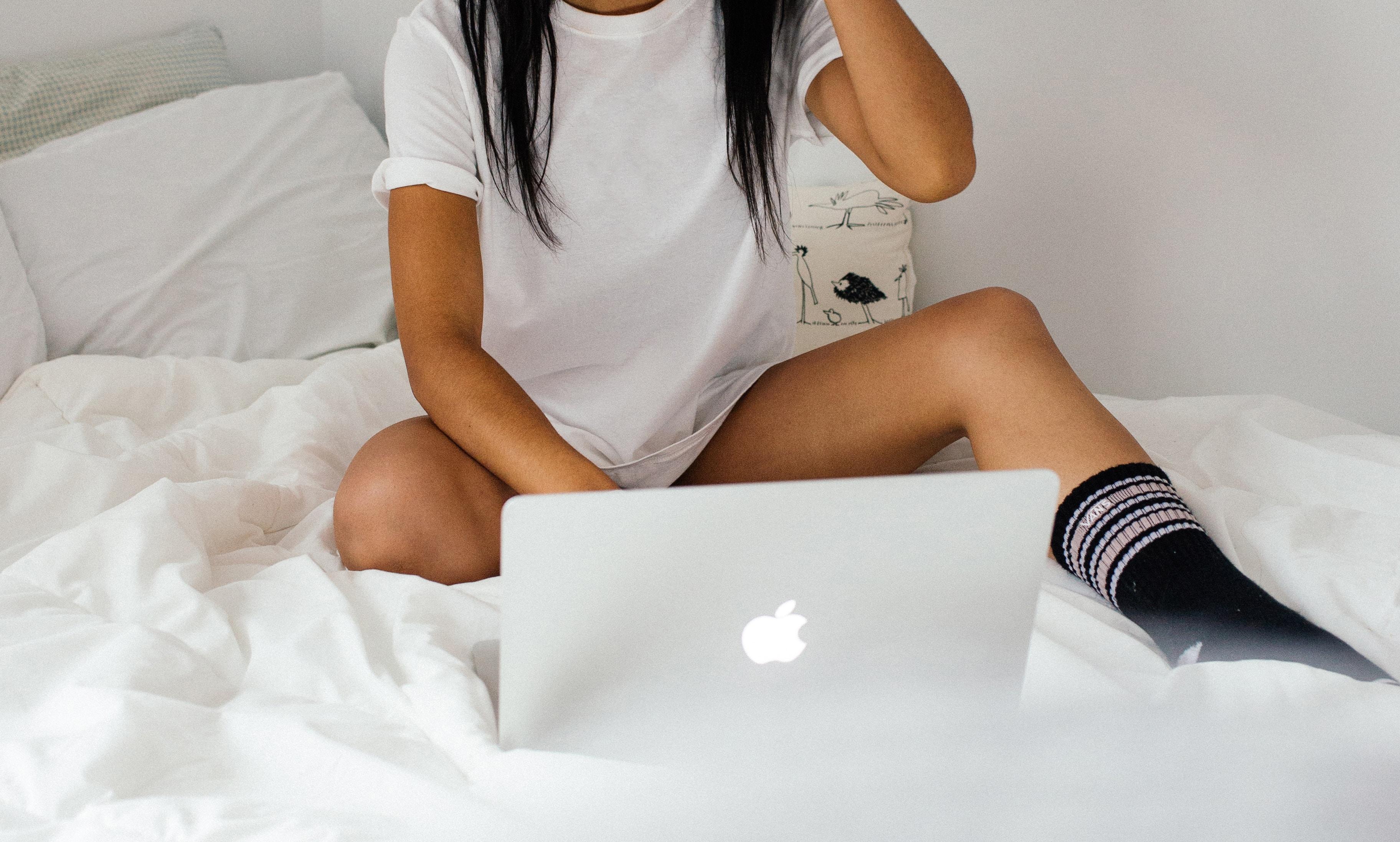 Una mujer consulta su ordenador en la cama. Foto: Charles