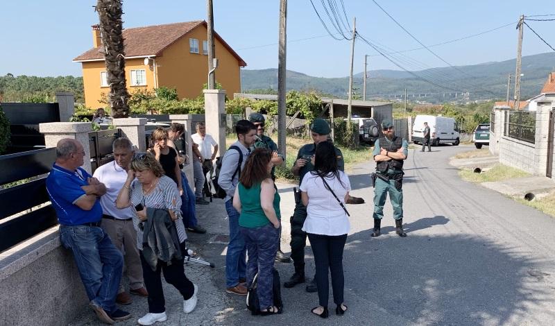 Agentes de la Guardia Civil y vecinos ante el domicilio de las tres víctimas del crimen en el concello de Valga. EP