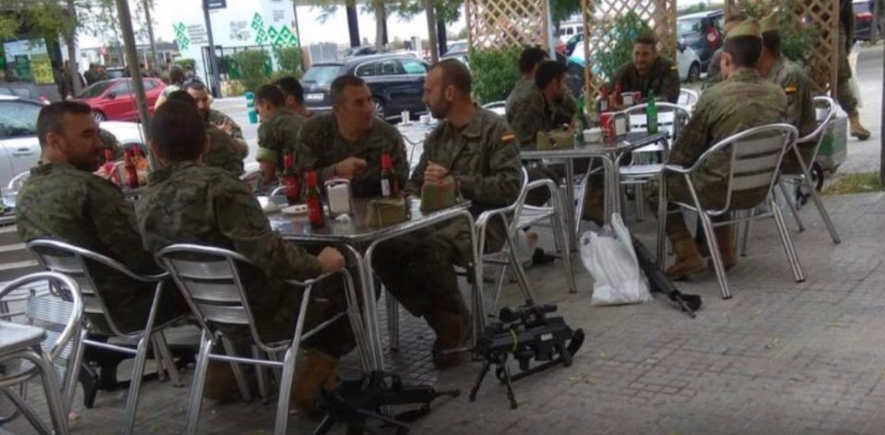 Legionarios toman cervezas en una terraza con sus armas en el suelo