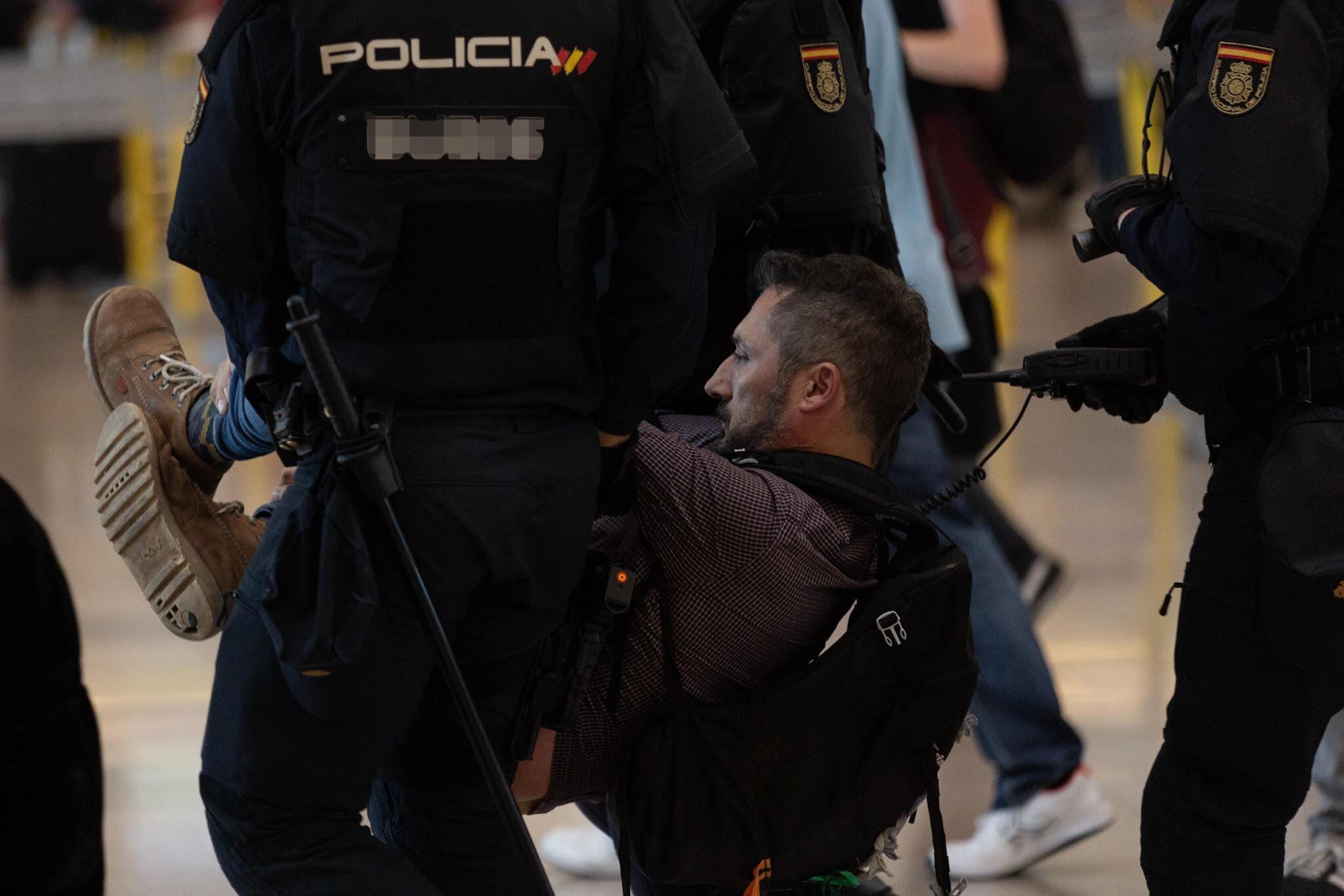 Agentes de la Policía Nacional se llevan a uno de los concentrados en el Aeropuerto de Barcelona El Prat. 