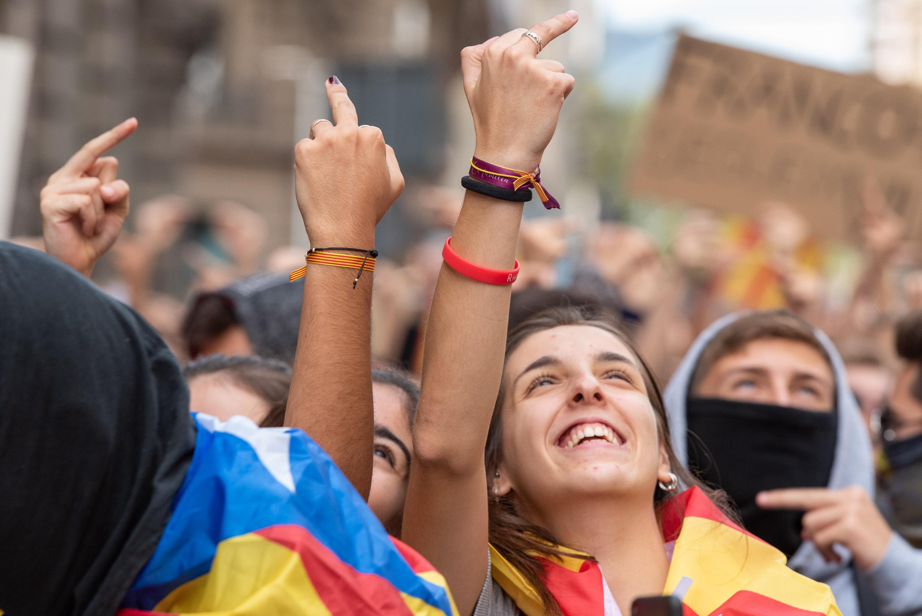 Jóvenes con banderas de la estelada levantan el dedo corazón mirando hacia arriba durante la manifestación estudiantil organizada en la Plaza de la Universidad de Barcelona. EP