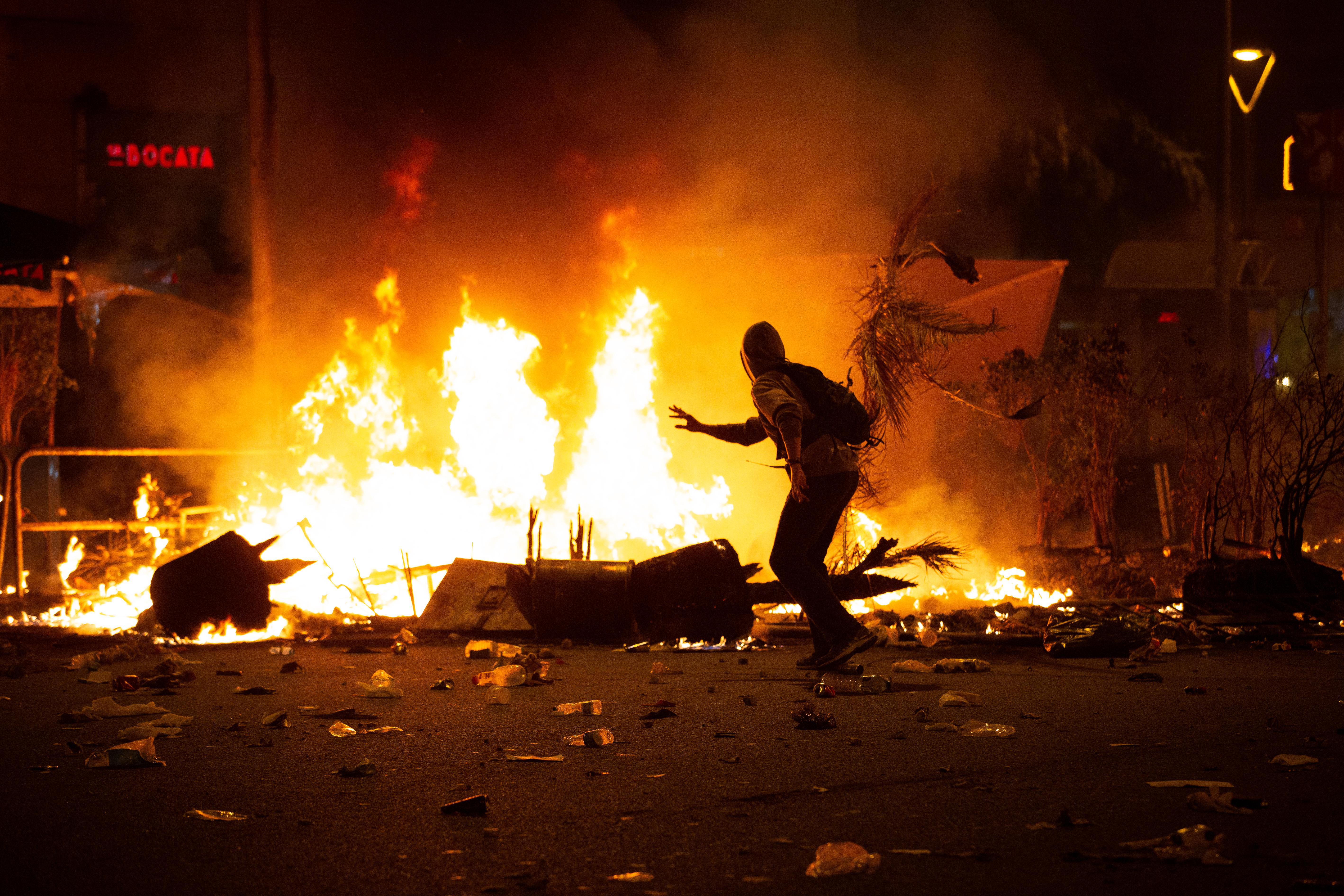 Un manifestantes corre frente al fuego durante los disturbios en la Plaza de Urquinaona en Barcelona a 18 de octubre de 2019 