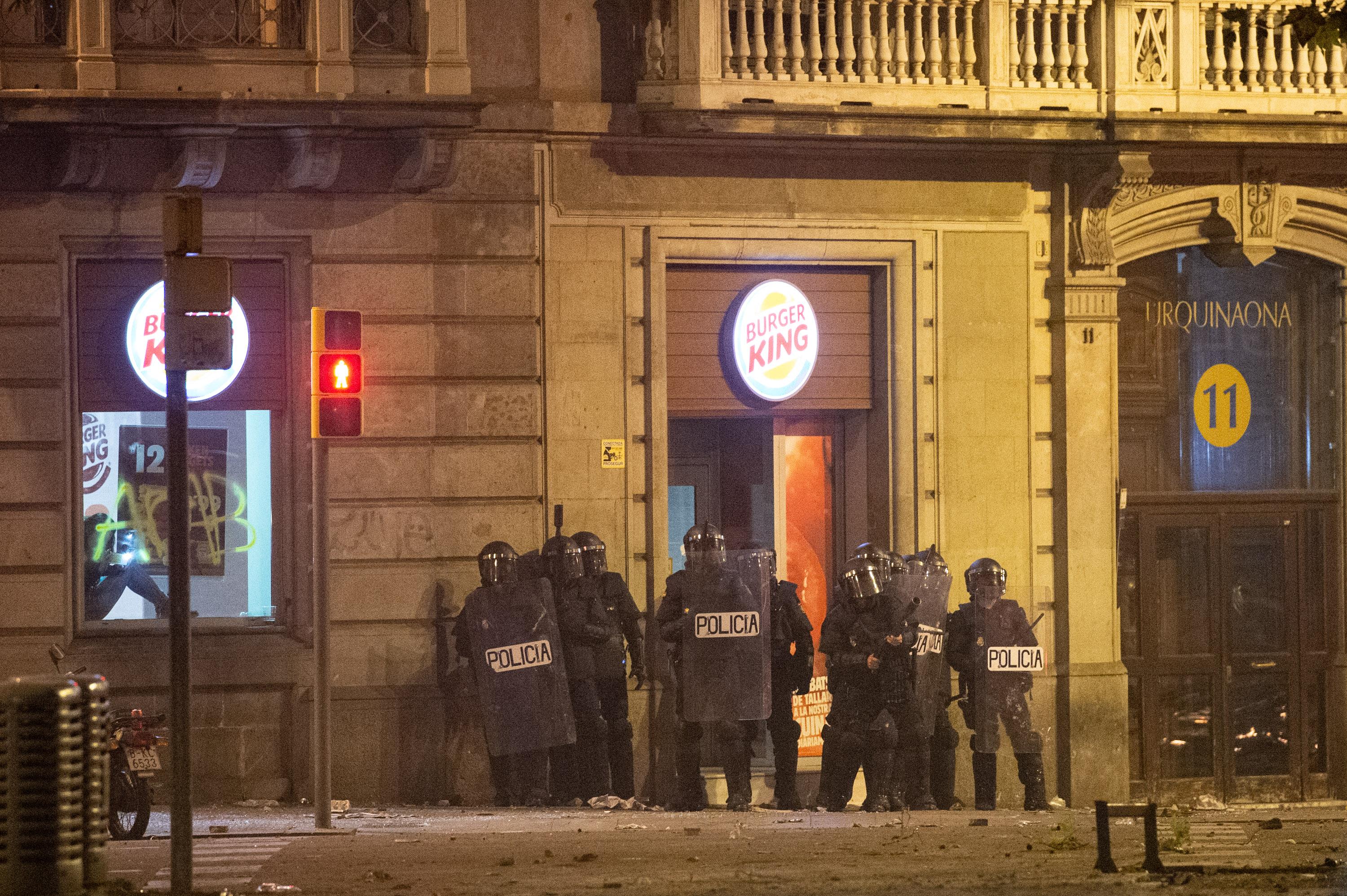 Agentes de la Policía Nacional a las puertas de un establecimiento durante los disturbios en la Plaza de Urquinaona en Barcelona a 18 de octubre de 2019 