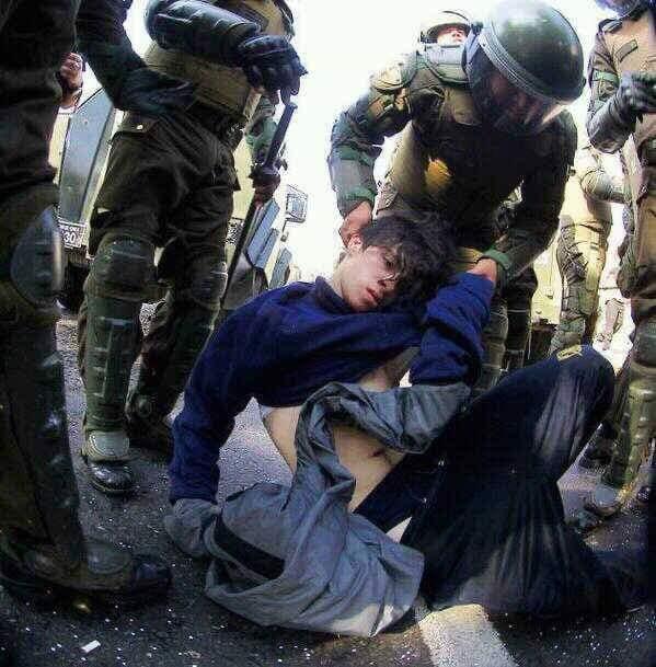 Un militar agarra del pelo e intenta levantar a un hombre aturdido en el suelo. Fuente: Redes sociales.
